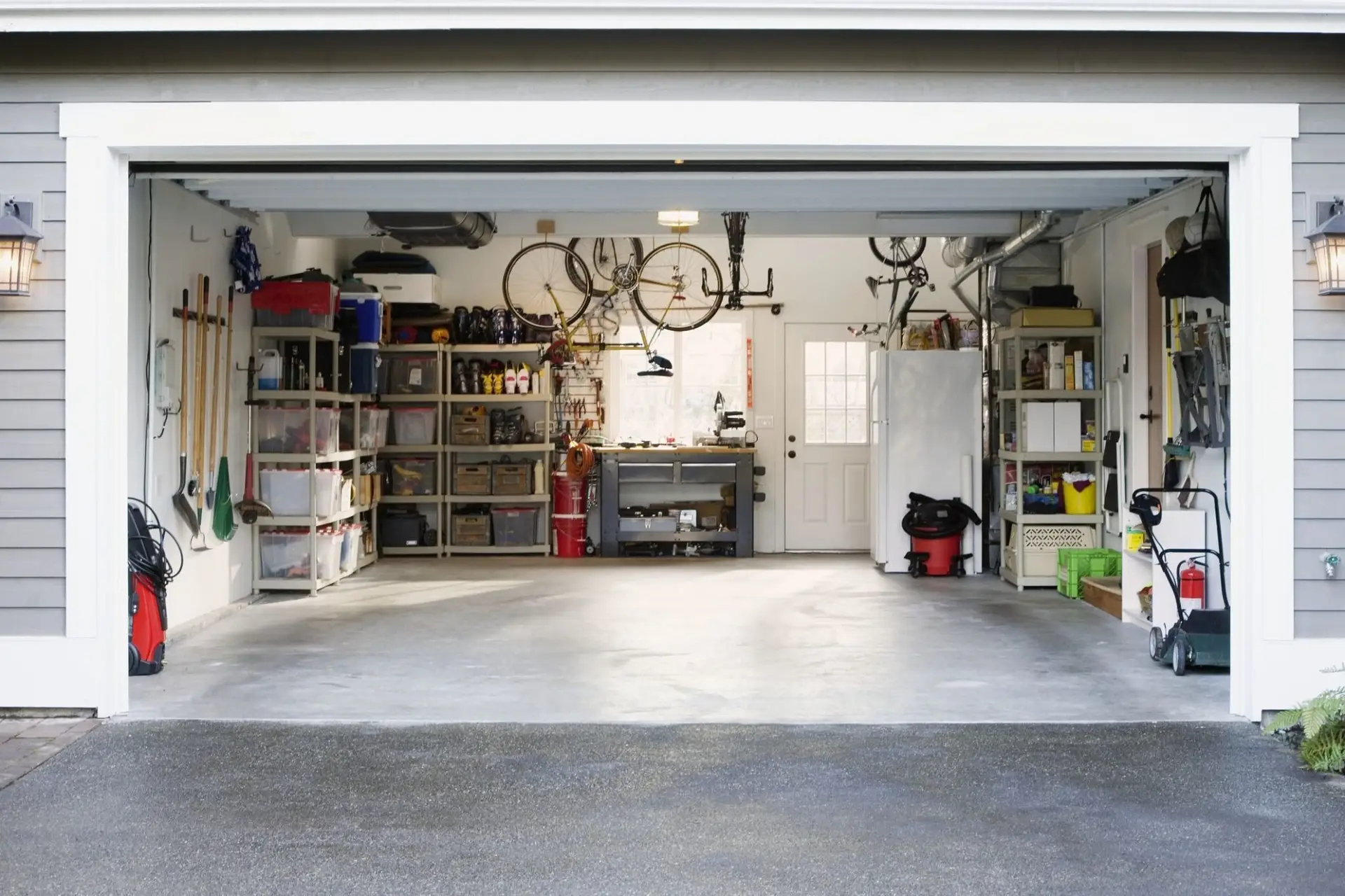 Garage Clean Up Service result: brightly lit, organized garage with grey shelves and wall-mounted garden tools, creating a clutter free garage space.