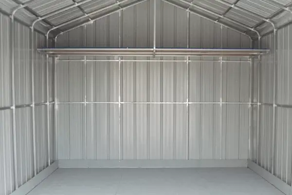 Interior view of a completely empty metal storage shed with corrugated walls, metal roof framing, and a clean concrete floor Shed Clean Outs Service ans also Junk and Clutter Removal in Seattle WA