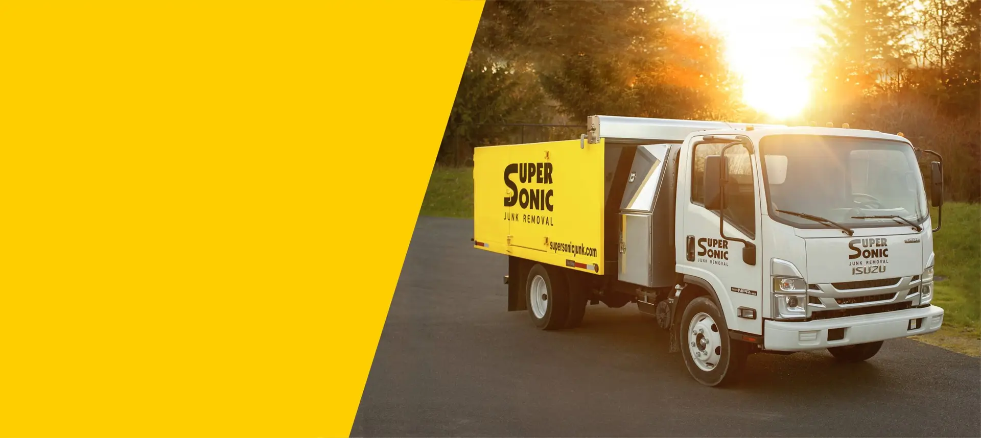 Branded Super Sonic Junk Removal truck with a yellow cargo body parked outdoors at sunset beside a bold yellow diagonal graphic block